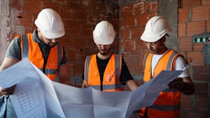three men in hard hats looking at construction plans
