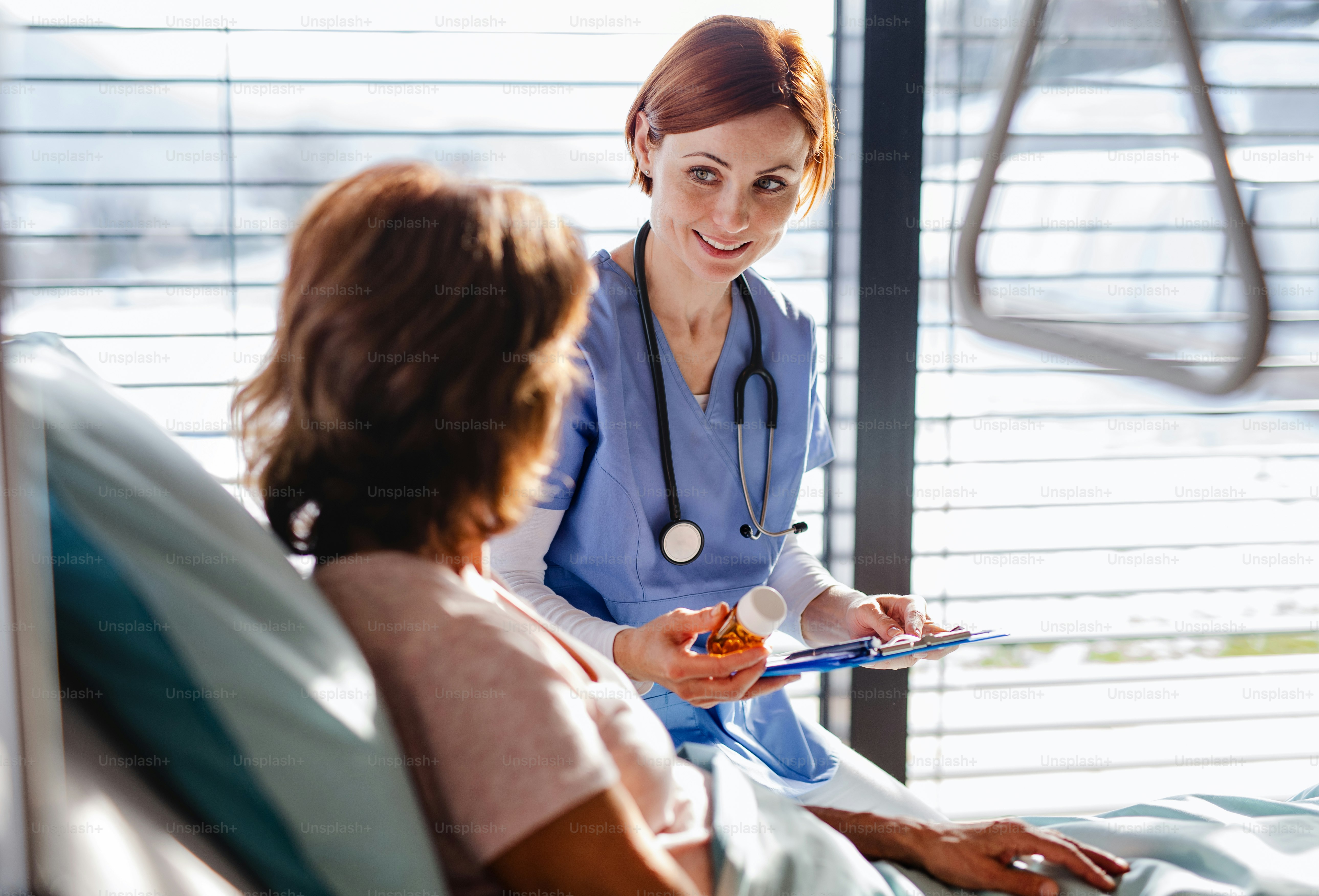 Eine freundliche Ärztin untersucht einen älteren Patienten im Bett im Krankenhaus.