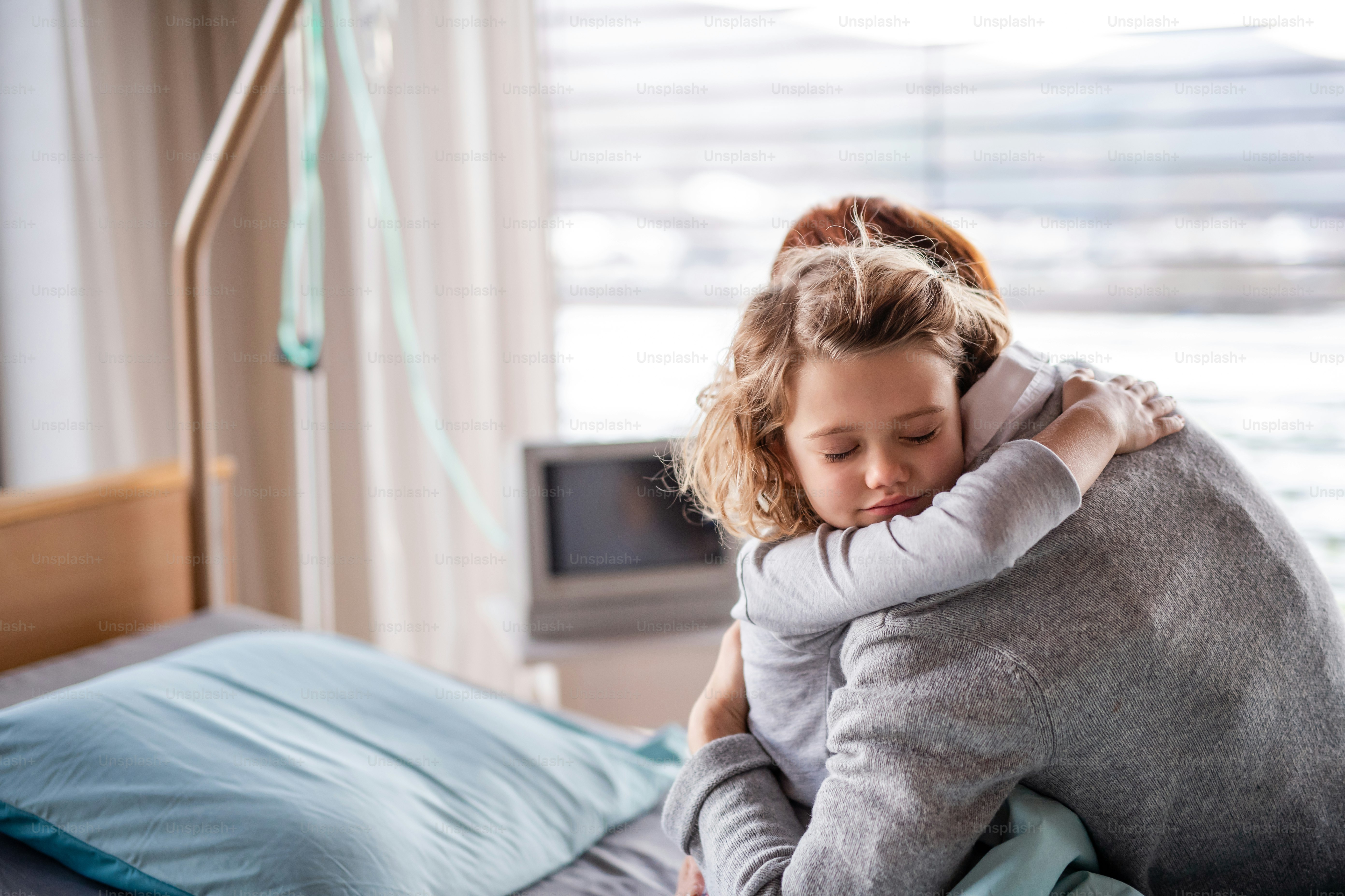 Caring mother visiting sleeping small girl daughter in hospital, hugging