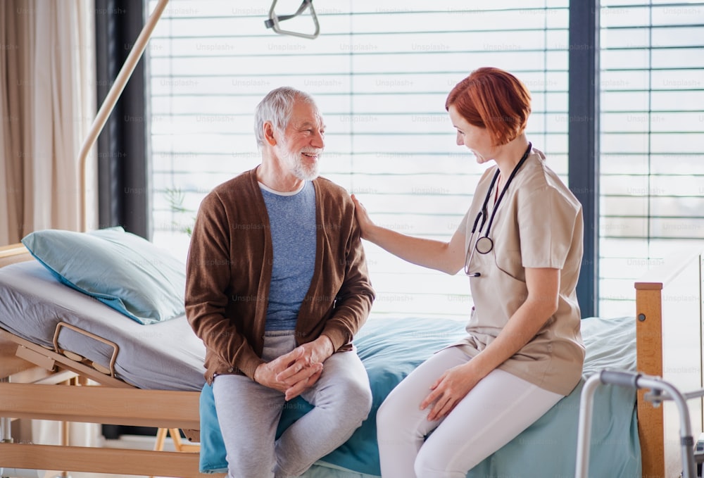 Uma simpática médica conversando com paciente idosa na cama no hospital.