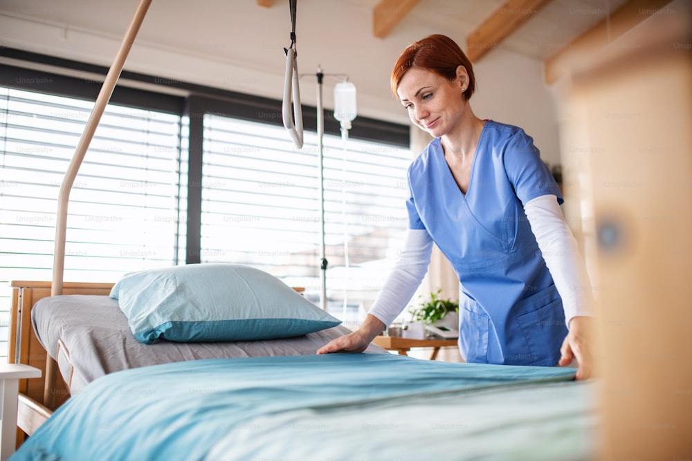 Ein Porträt einer Krankenschwester oder eines Reinigungspersonals, das im Krankenhaus die Bettwäsche wechselt.