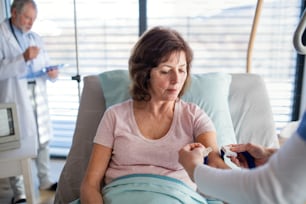 A doctor and nurse examining a senior woman patient in hospital.