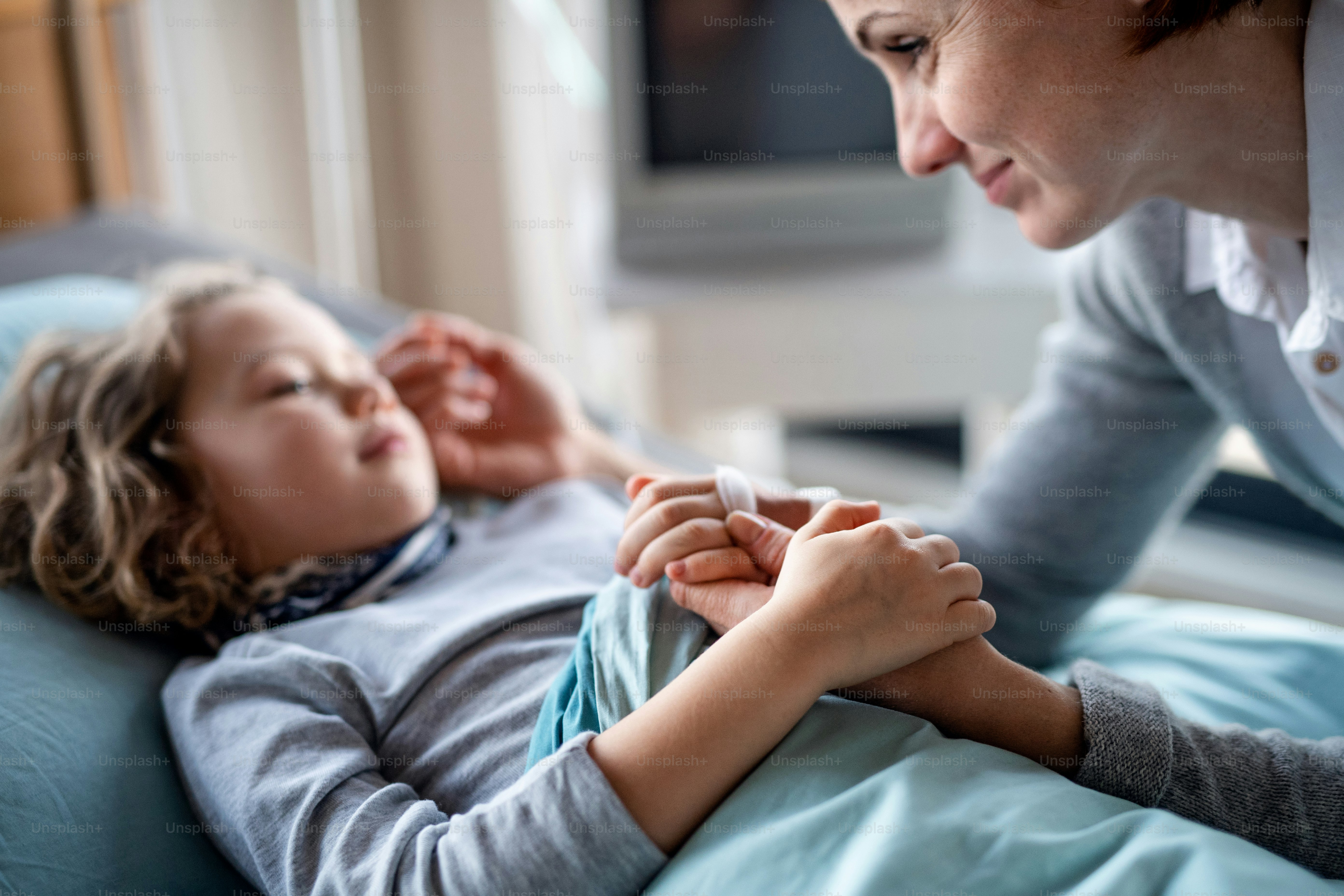 Fürsorgliche Mutter besucht kleine Mädchentochter im Bett im Krankenhaus, Mittelteil.