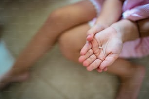 Midsection of unrecognizable small girl indoors, loosing baby tooth.