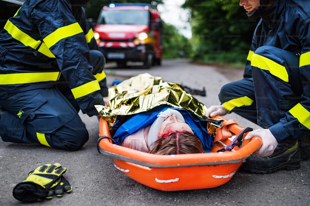 Uma jovem mulher ferida em uma maca de plástico após um acidente de carro, coberta por cobertor térmico. De perto.