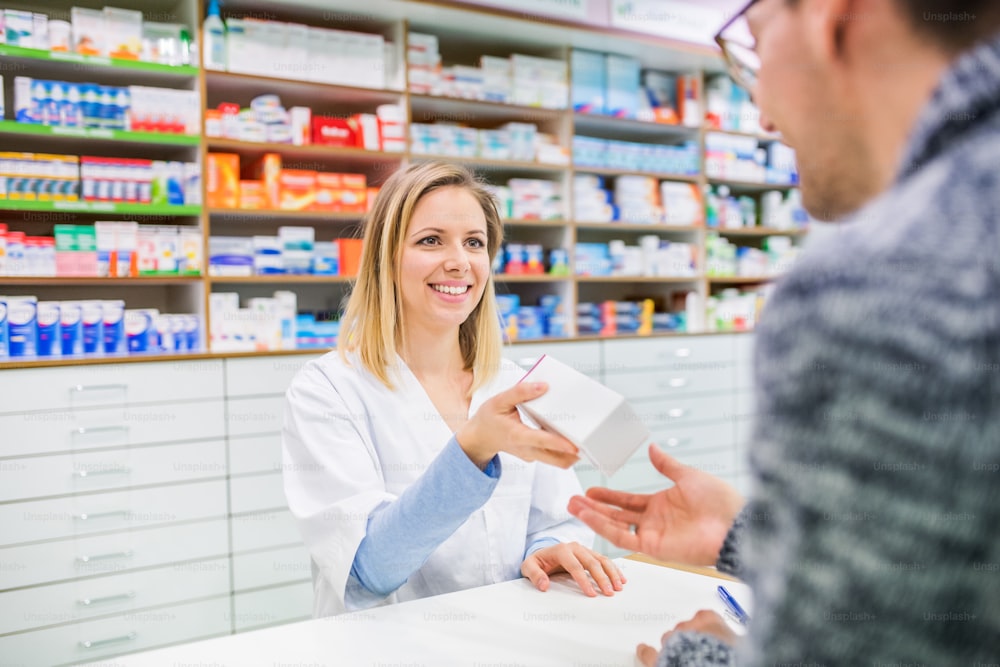 Female friendly pharmacist serving an unrecognizable male customer.