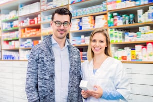 Portrait of a female friendly pharmacist with a male customer or a colleague.