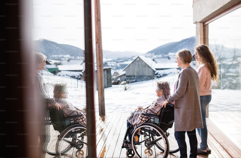 집에서 휠체어를 탄 어머니와 할머니와 함께 있는 십대 소녀. 가족과 세대 개념입니다.