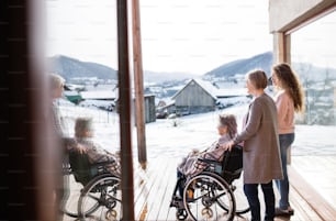 自宅で車椅子に乗った母親と祖母を持つ10代の少女。家族と世代のコンセプト。