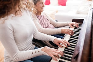 車椅子の祖母を持つ10代の少女が家でピアノを弾く。家族と世代のコンセプト。