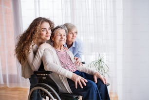 A teenage girl with her mother and grandmother in wheelchair at home. Family and generations concept.
