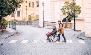 휠체어를 탄 아버지와 산책하는 어린 아들. 장애인 노인을 돕는 간병인.