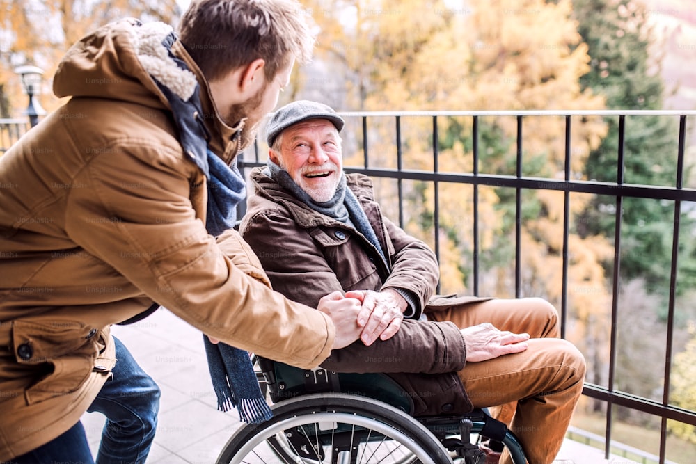 Pai em cadeira de rodas e filho pequeno em uma caminhada. Um cuidador que auxilia o idoso com deficiência.
