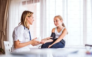 オフィスで小さな女の子の血圧をチェックする若い女医。
