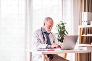 Senior male doctor working on laptop at the office desk.