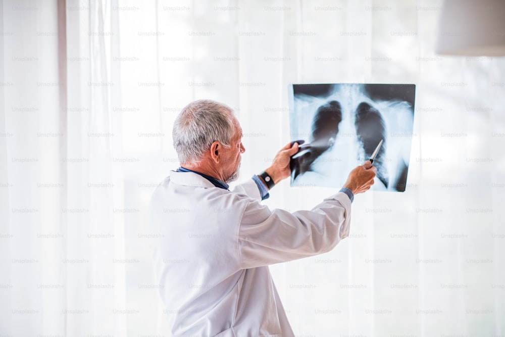 Oberarzt betrachtet das Röntgenbild des Brustkorbs in seinem Büro. Männlicher Arzt mit Smartwatch untersucht ein Röntgenbild.