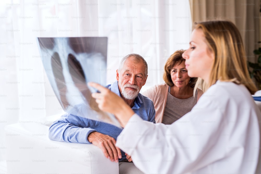 Ärztin mit Röntgenbild spricht mit einem älteren Ehepaar im Büro.