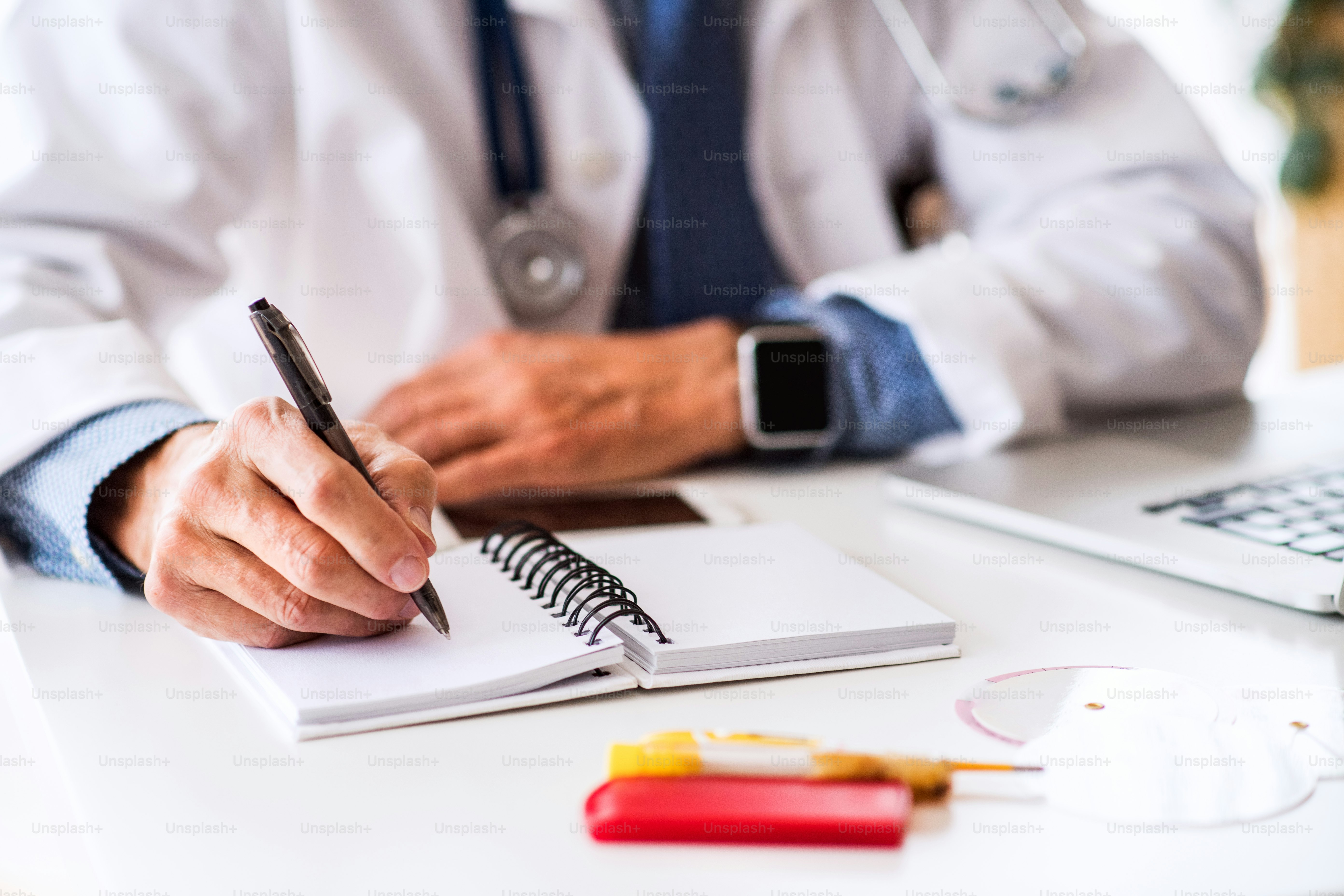 Médico masculino senior irreconocible trabajando en el escritorio de la oficina.