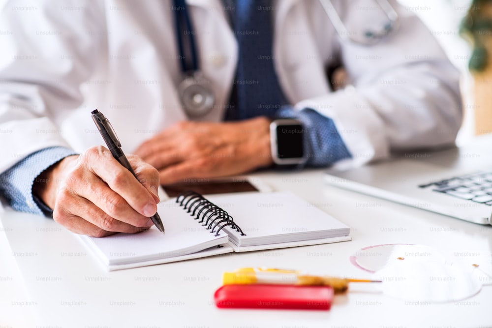 Unrecognizable senior male doctor working at the office desk.