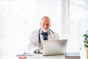 Senior male doctor working on laptop at the office desk.