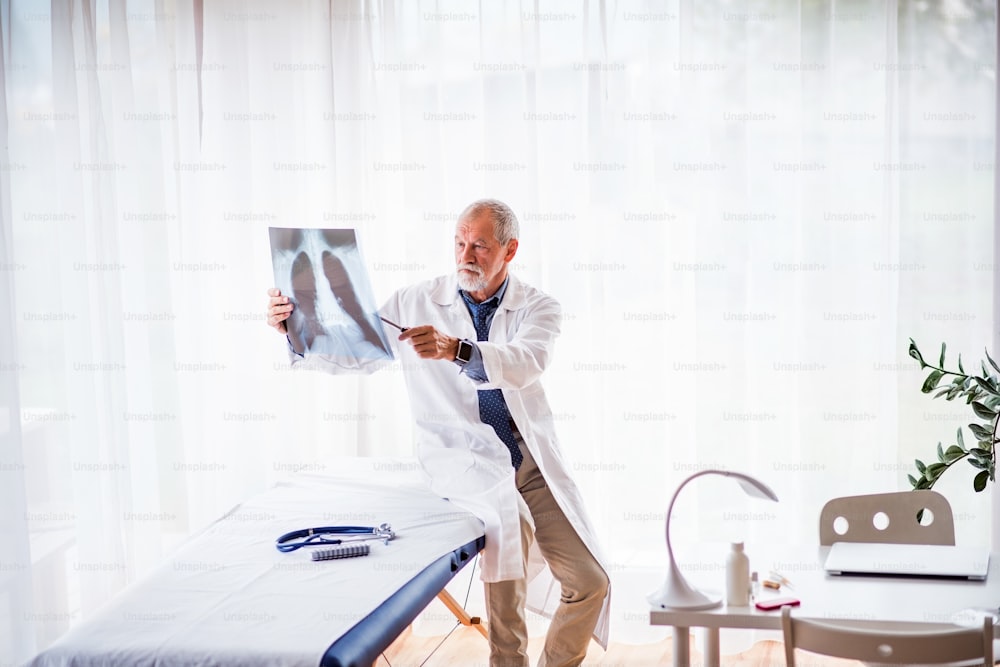 Médico principal mirando la radiografía de tórax en su consultorio. Médico masculino con reloj inteligente examinando una radiografía.