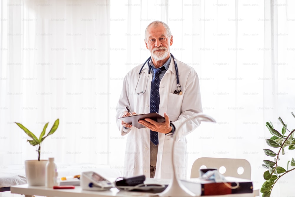 Senior doctor in his office. Male doctor with smartwatch making notes.