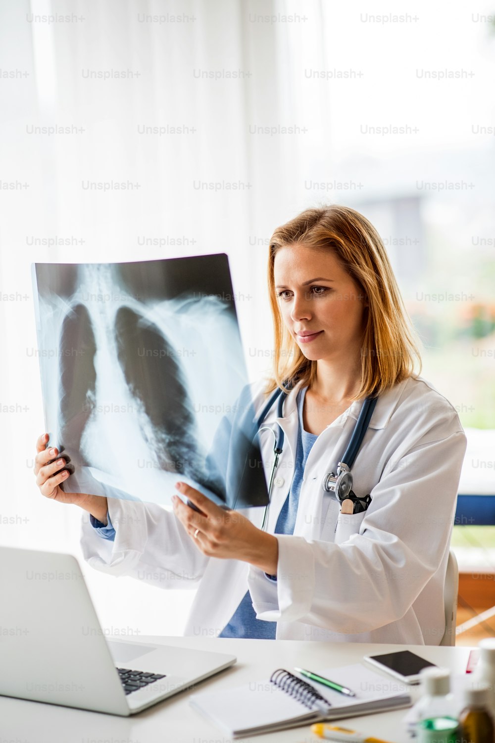 Jeune femme médecin avec ordinateur portable au bureau. Médecin examinant une radiographie.