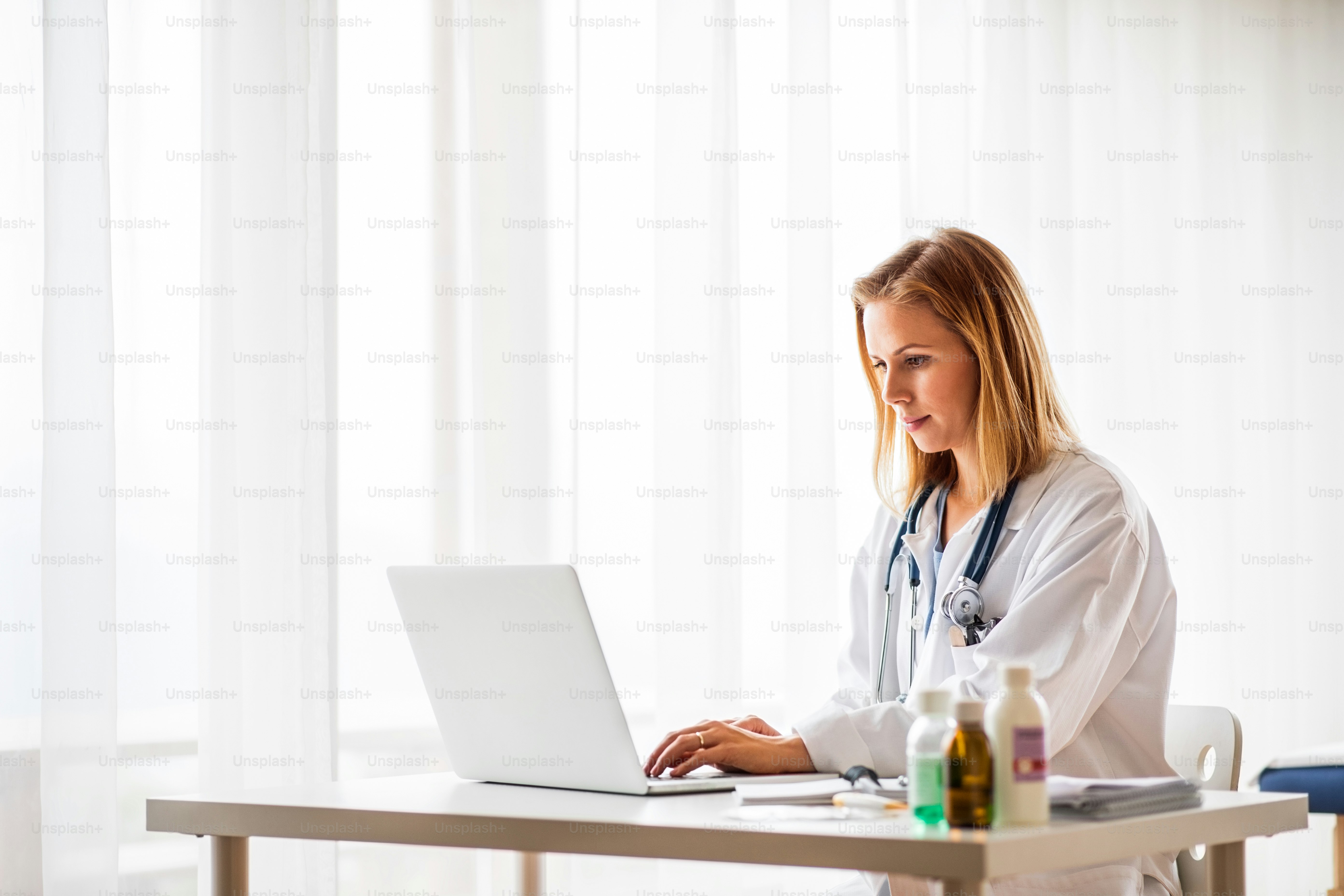 Young female doctor working on laptop at the office desk