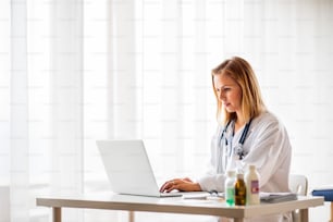 Young female doctor working on laptop at the office desk.