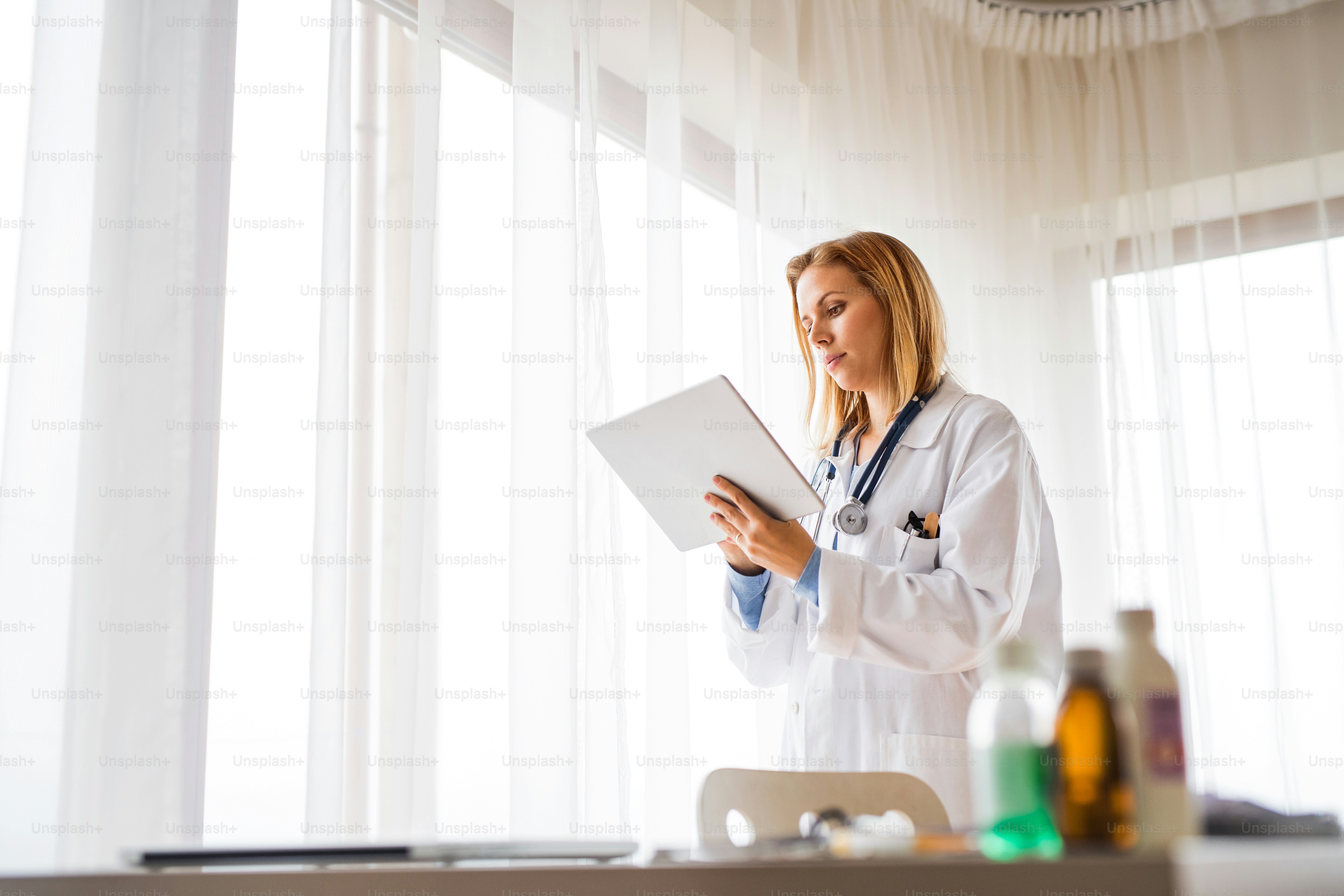 Young female doctor with tablet working at the office