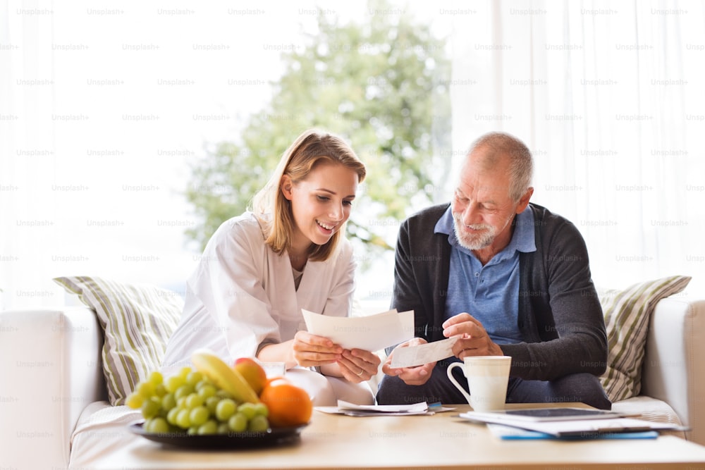 Visitante de saúde e um homem idoso durante a visita domiciliar. Uma enfermeira ou um médico discutindo os resultados dos testes.