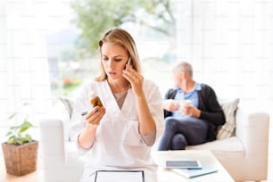 Visiteur de santé avec smartphone et un homme âgé lors de la visite à domicile. Une infirmière ou un médecin qui passe un coup de fil.