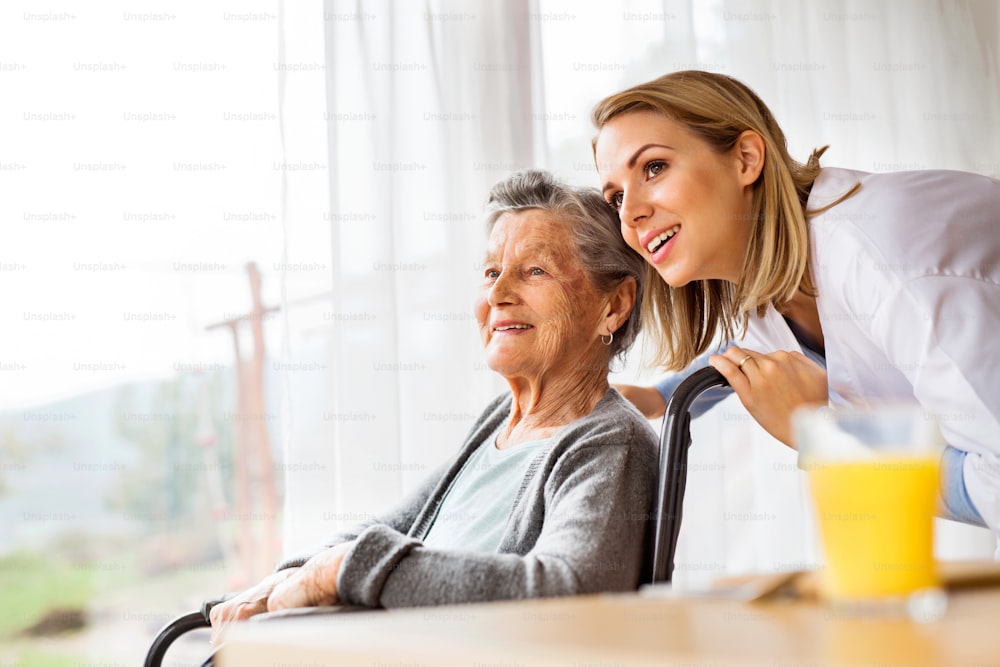 Gesundheitsbesucher und eine ältere Frau beim Hausbesuch. Eine Krankenschwester im Gespräch mit einer älteren Frau im Rollstuhl.