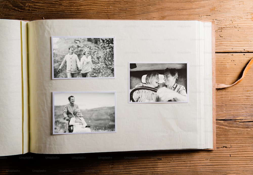 Photo album with black-and-white pictures of senior couple in love. Studio shot on wooden background.