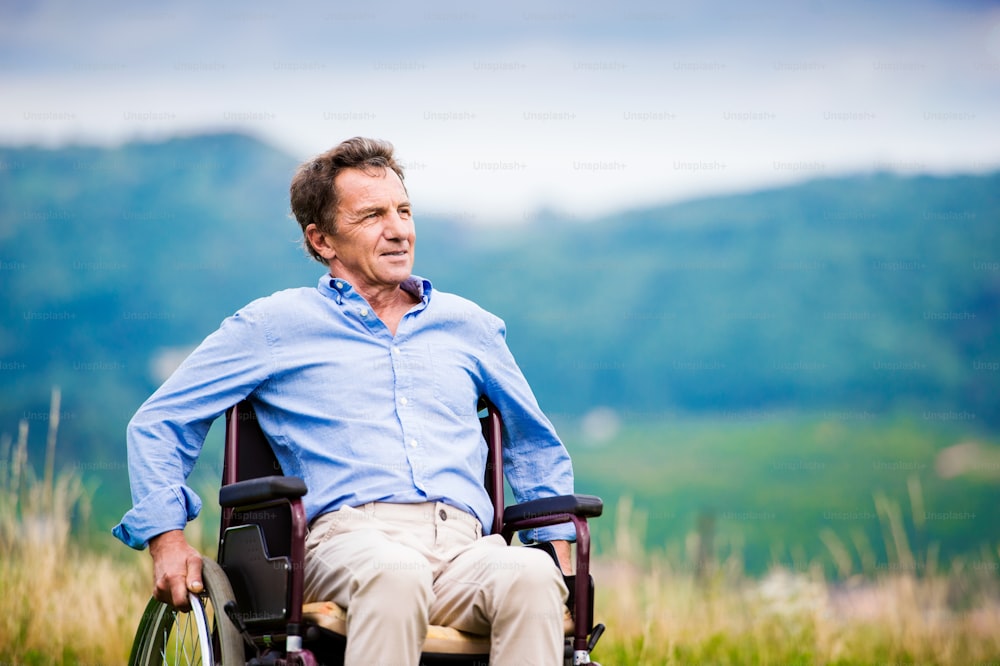 Senior man in wheelchair outside in nature