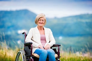 Femme âgée en fauteuil roulant à l’extérieur dans la nature