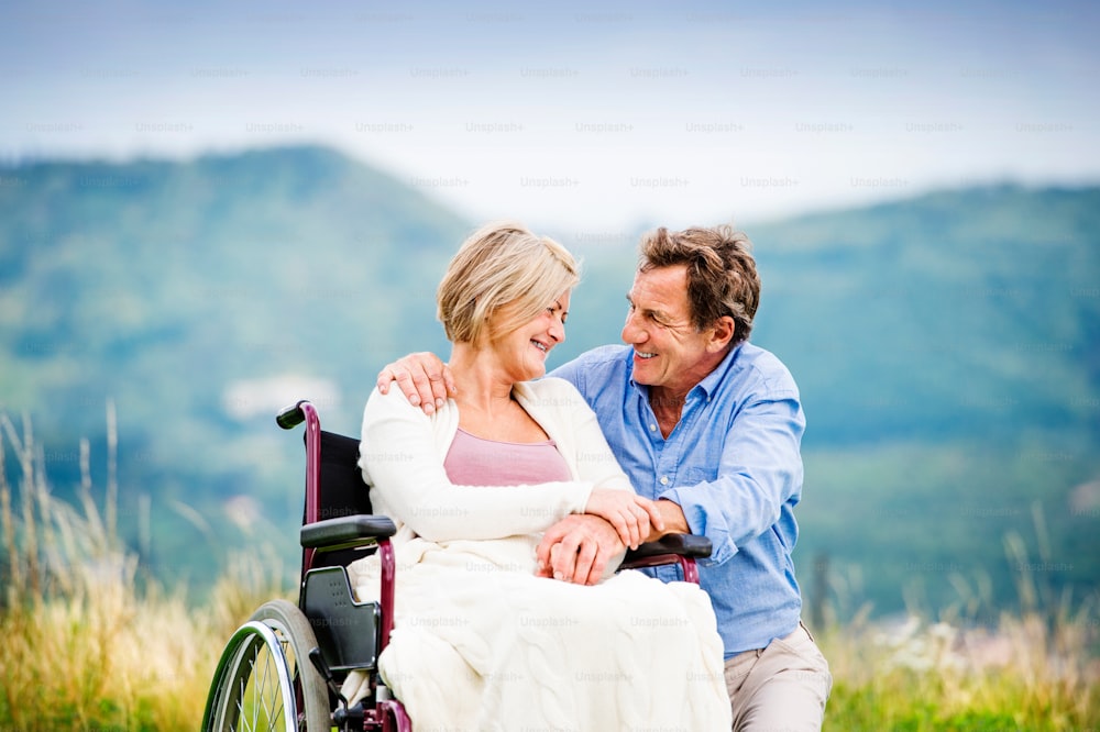 Uomo anziano con la donna in sedia a rotelle fuori in natura