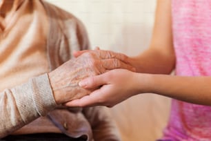 Unrecognizable grandmother and her granddaughter holding hands.