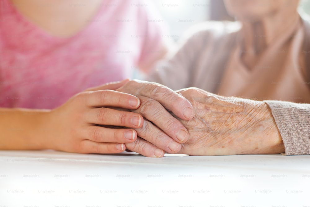 Unrecognizable grandmother and her granddaughter holding hands.