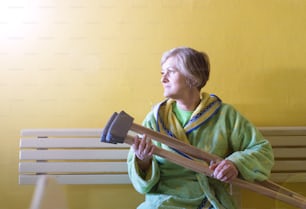 Senior woman injured sitting in the hallway of hospital holding crutches