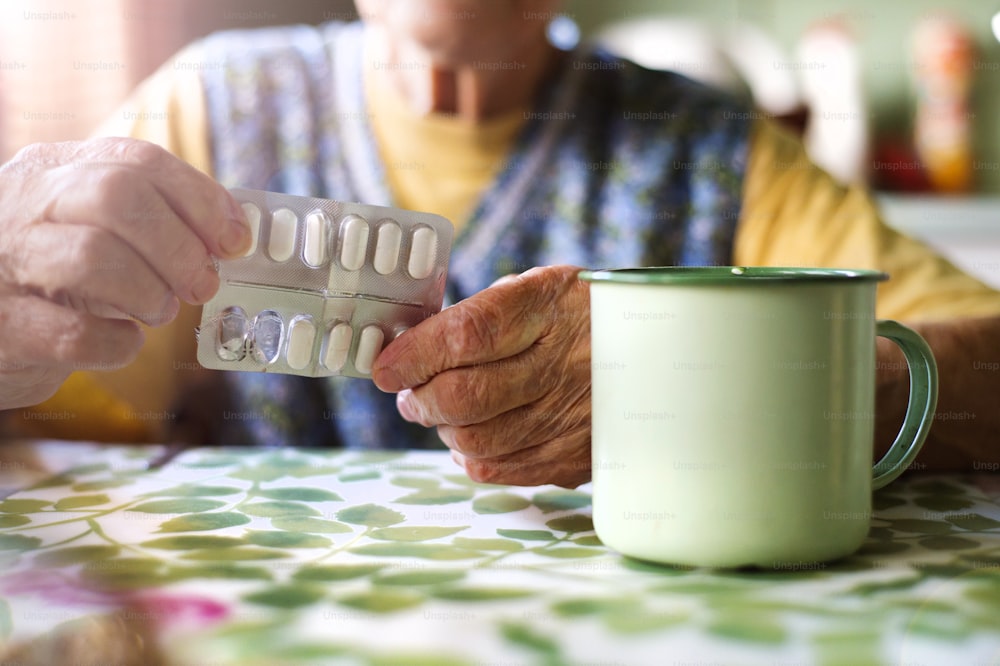 Close up of old woman's hands holding pills in kitchen kitchen
