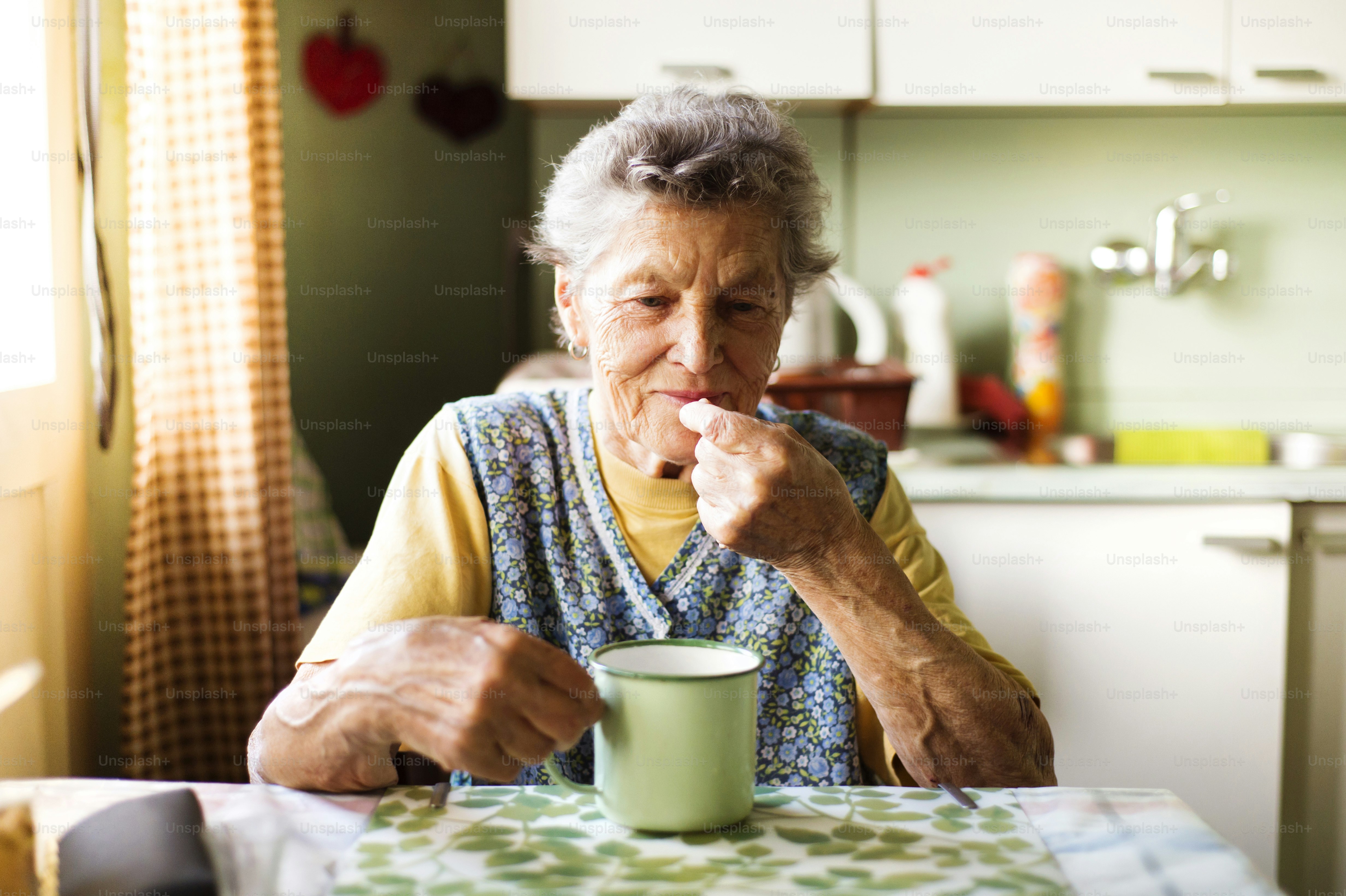 Old woman is taking pills in her country style kitchen