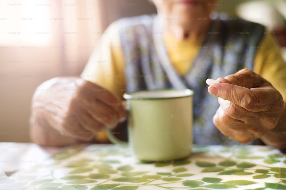 Old woman is taking pills in her country style kitchen