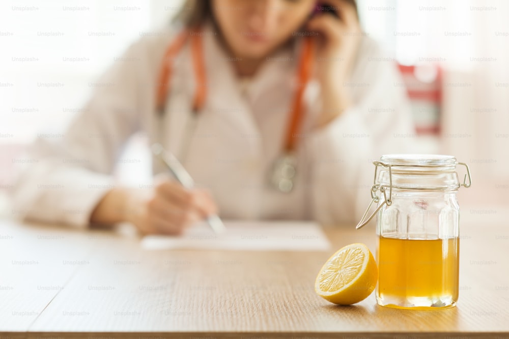 Détail du miel et du citron avec la femme médecin en arrière-plan
