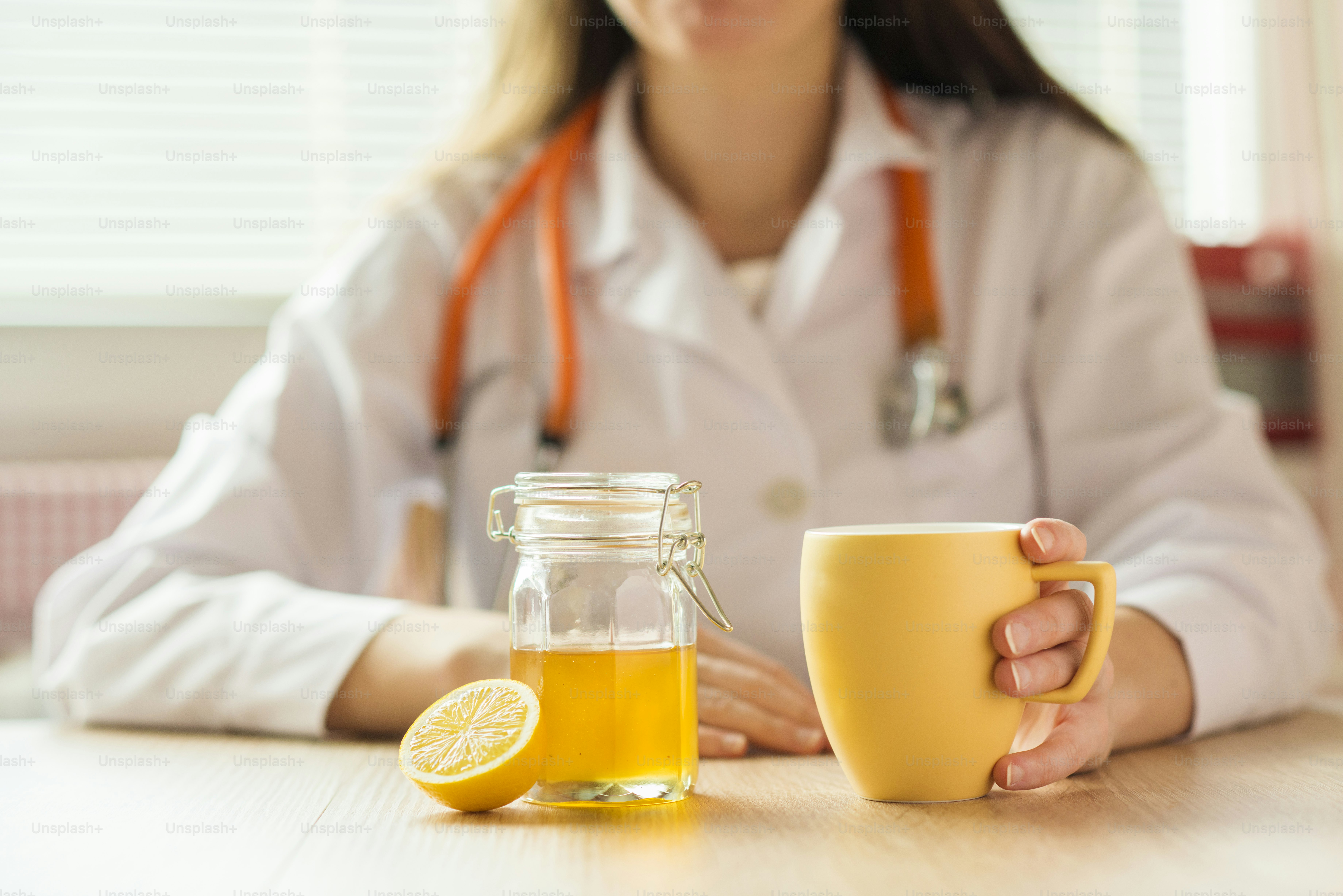 Detail - honey, lemon and cup of tea with doctor woman in background