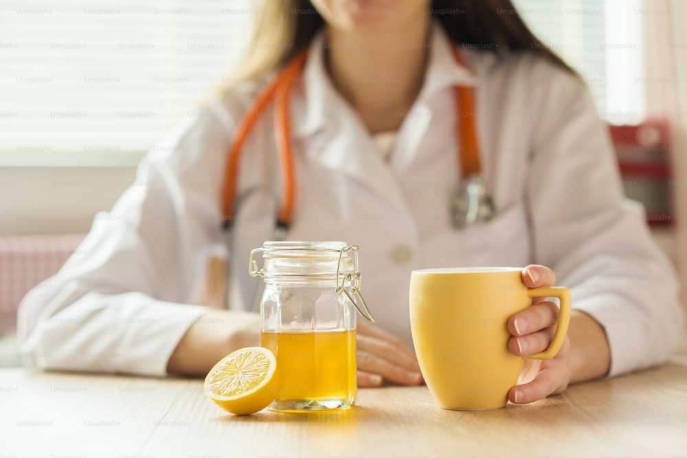 詳細 - 蜂蜜、レモン、お茶の背景に医師の女性