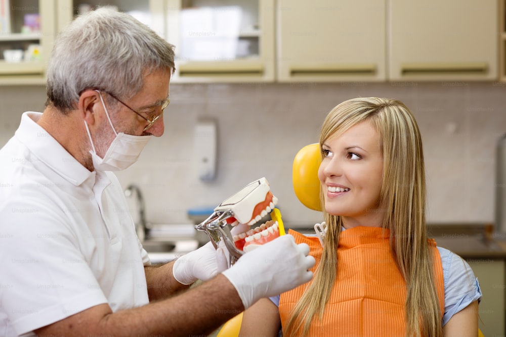 Il dentista sta mostrando la tecnica di pulizia dei denti al suo paziente
