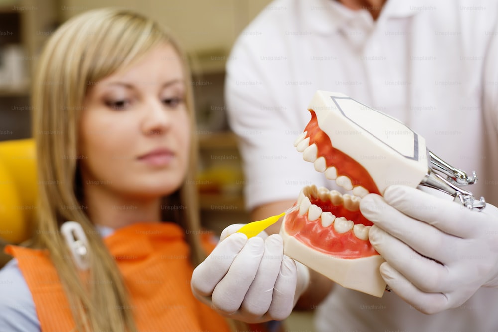 치과 의사는 환자에게 치아 청소 기술을 보여주고 있습니다