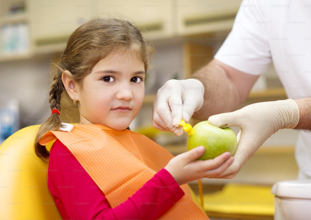 Dentist is showing the technique of teeth cleaning to a little girl