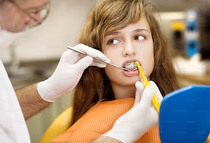 Teenage girl with the braces on her teeth is having a treatment at dentist